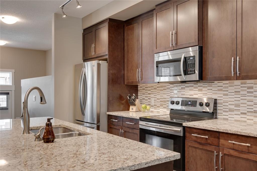 Full-height cabinetry, tile backsplash, and stainless appliances.