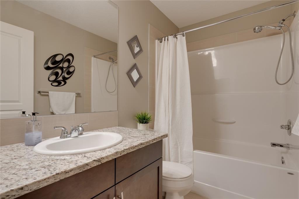 Full bathroom finished with granite counters and tile surround.